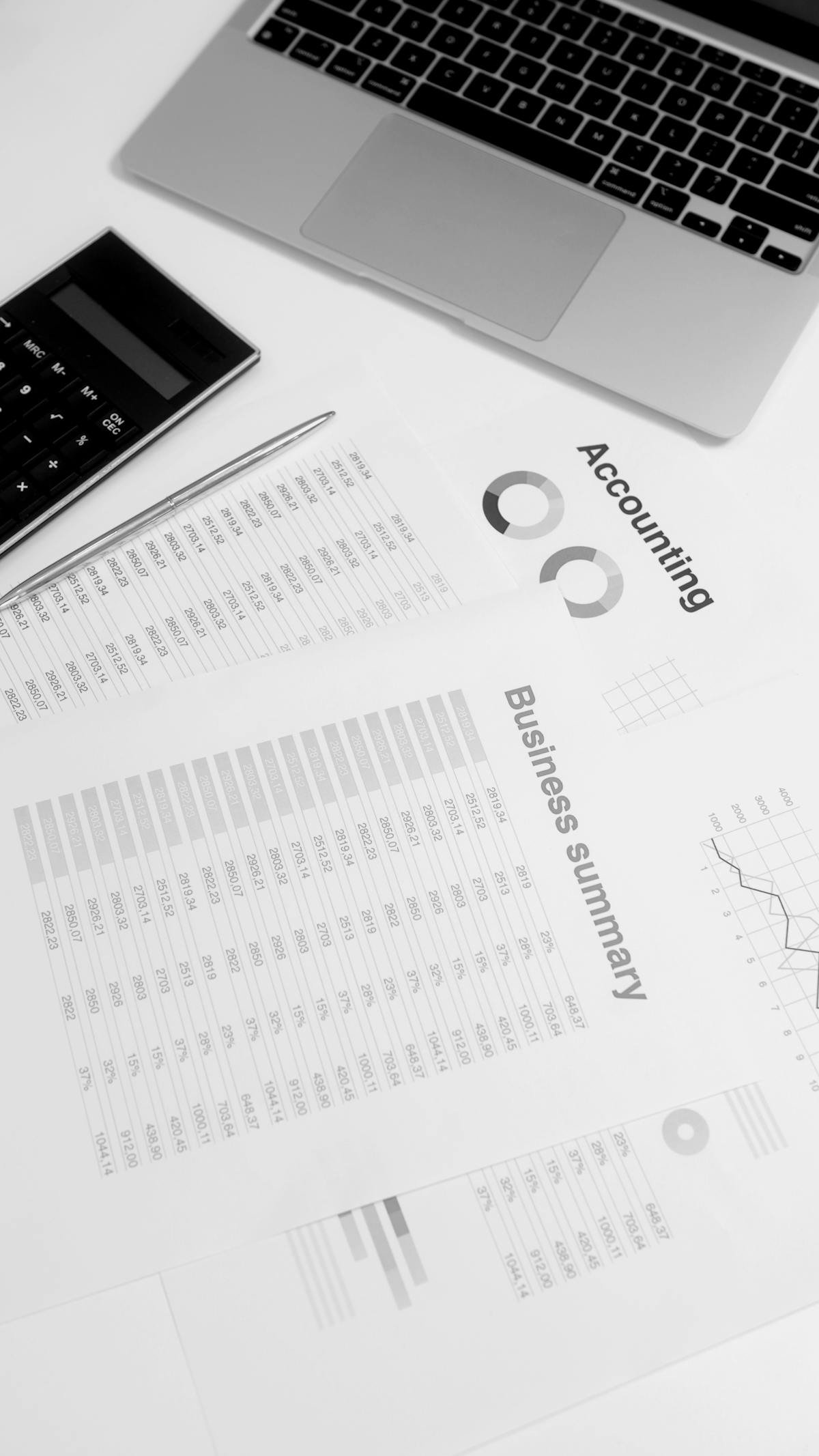 Mesa de trabalho com relatórios de dados e laptop representando análise de CRM imobiliário